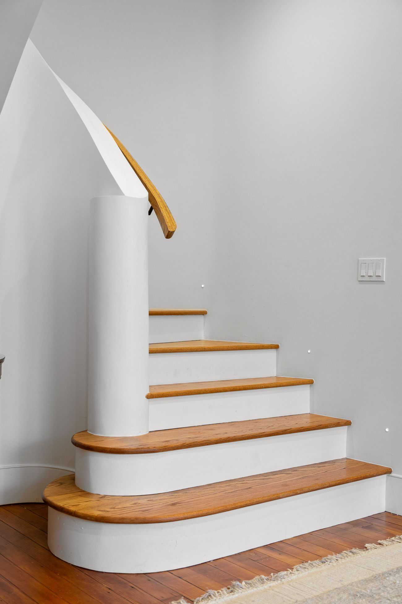 Custom curved staircase detail in oak and plaster