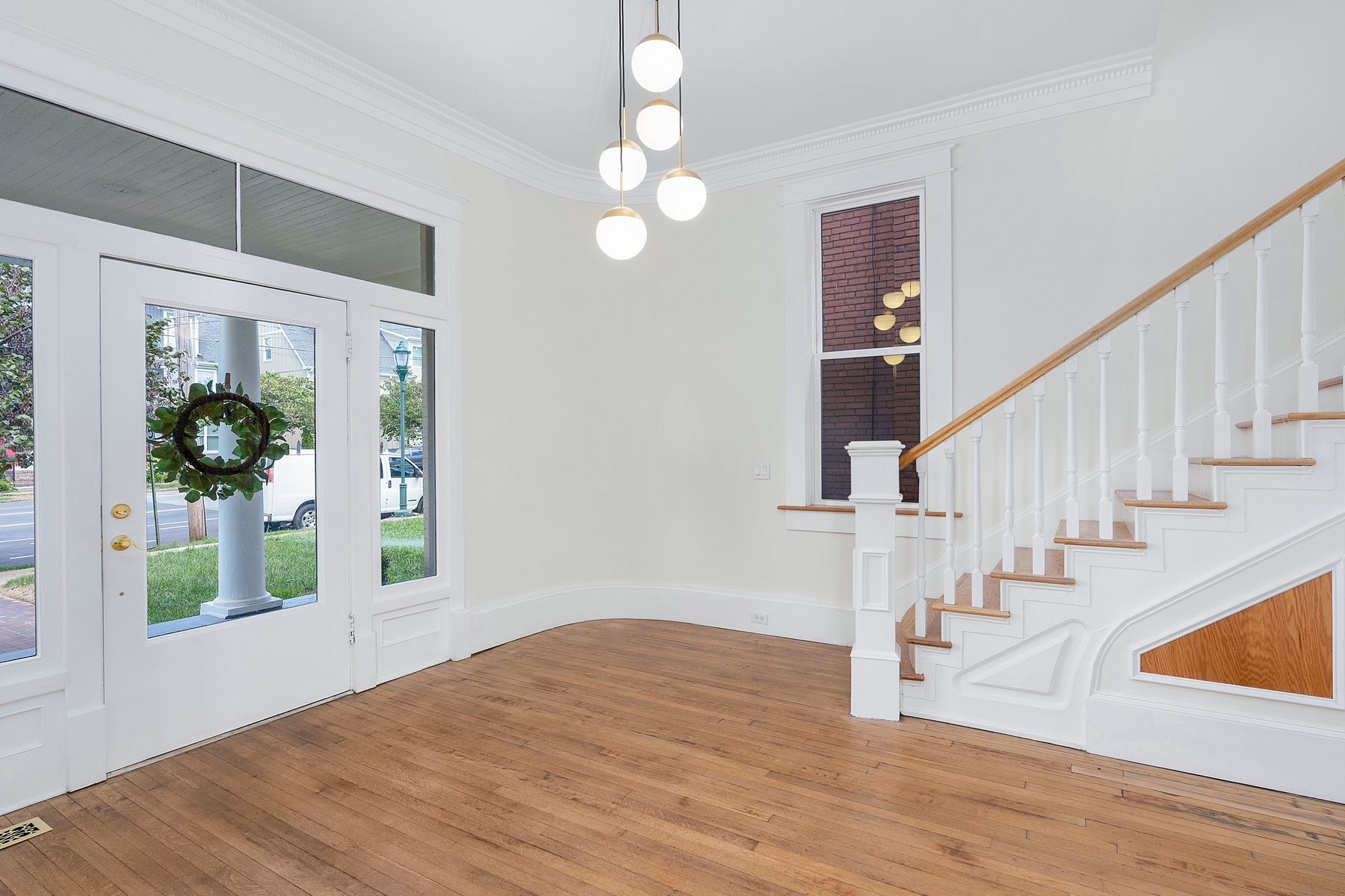 Entry hall with refinished oak floors and a restored white spindle staircase at 904 East Martin Luther King Boulevard