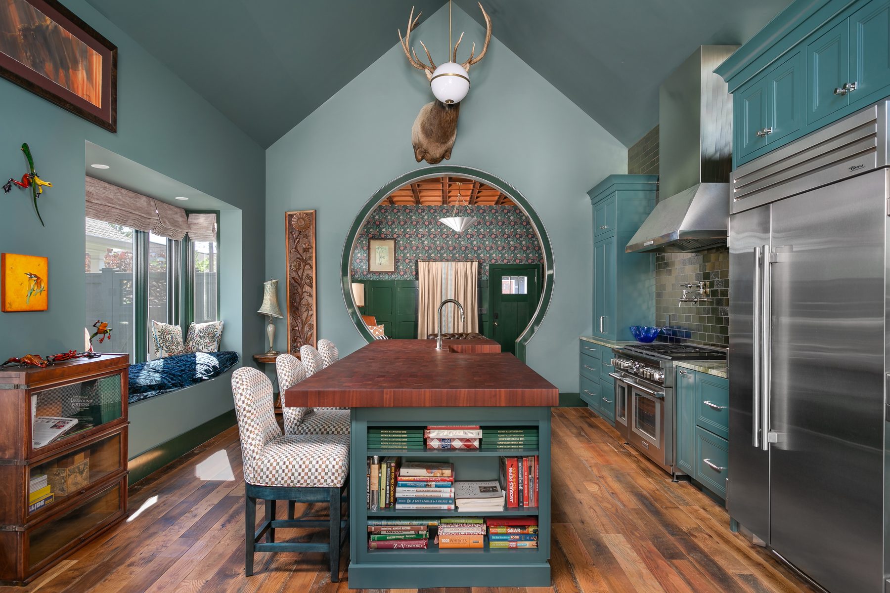 Craftsman kitchen and living room in deep green with a custom round window and butcher-block island